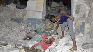 A Somali man inspects the lifeless bodies of civilians caught in the blast from a suicide car bomb on a hotel in Mogadishu, Somalia, Friday, Feb, 26 2016. A suicide bomber rammed his car into a hotel's entrance in Mogadishu and blew it up, allowing Al-Shabab gunmen to force their way into the hotel, exchanging fire with hotel guards and leaving 14 dead before government security forces ended the attack, including four gunmen and the suicide bomber. (AP Photo/Farah Abdi Warsameh)